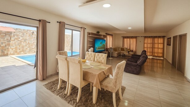 A spacious living area with a dining set, a sofa, and a TV. - Charming 3-bedroom chalet, with private pool, an with AC. (Malambo)