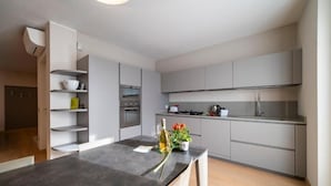 A modern kitchen with grey cabinets, a dark countertop, and a built-in oven. - VILLA La No. 1 - Spacious & Modern (MONTICELLI BRUSATI)