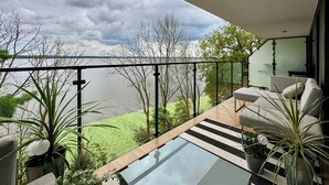 A balcony with a glass table, grey sofas, and potted plants. - Apartamenty Sun & Snow Lake House (Serock)