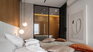 A modern hotel room with a large bed, a bathroom with a mirror, and a wall-mounted air conditioner. - Apartamenty Sun & Snow Lake House (Serock)