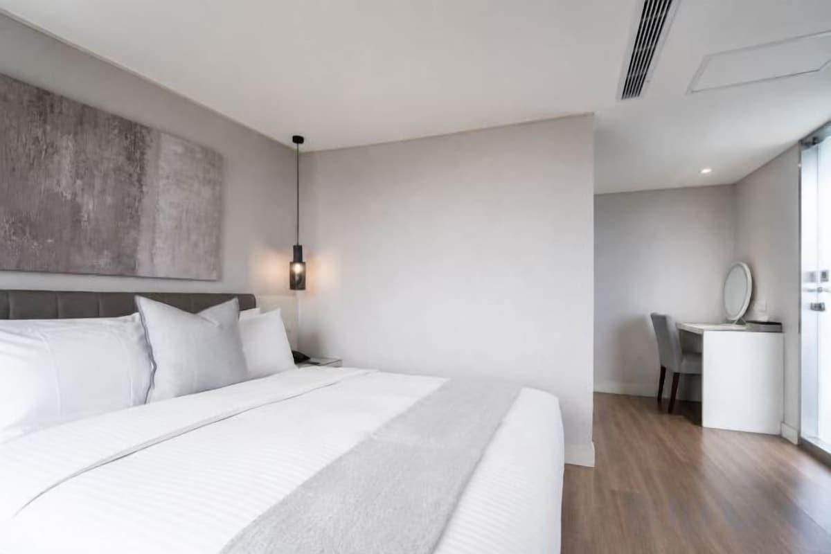 Una habitación de hotel moderna con una cama grande, un escritorio y una silla.