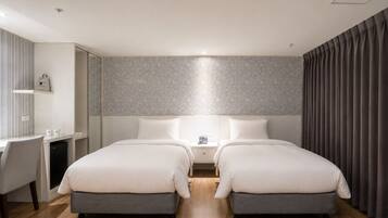 A hotel room with two beds, a desk, and a chair.