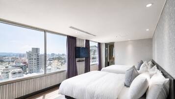Een hotelkamer met een groot bed, een televisie en uitzicht op de stad.
