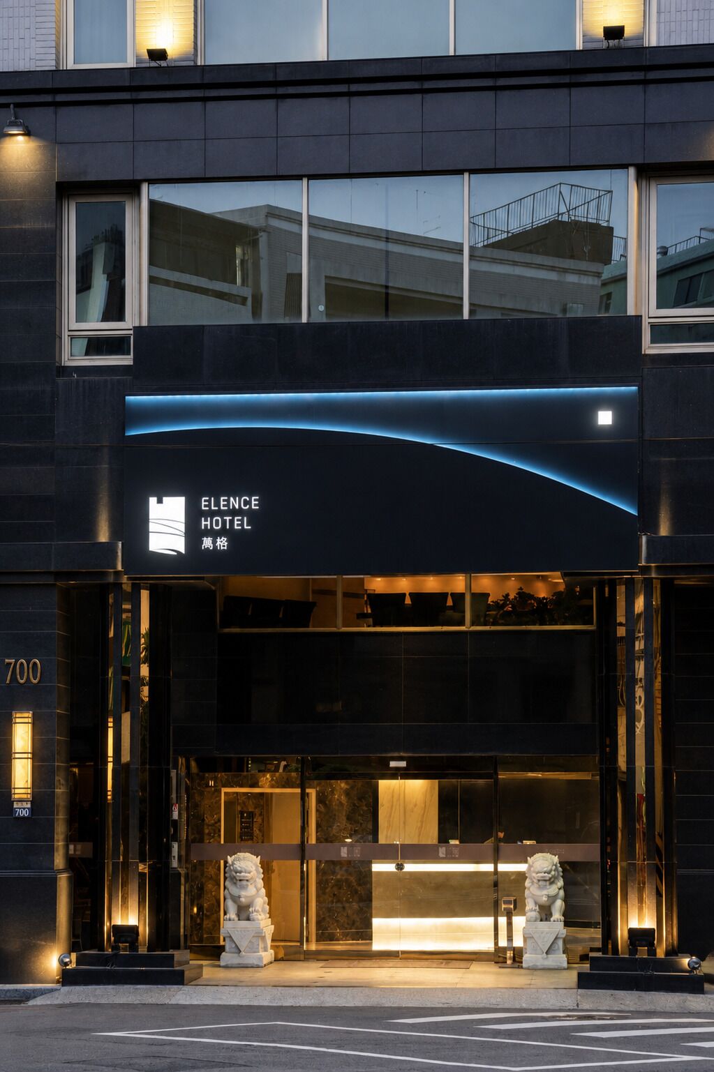 The exterior of the Elence Hotel with a modern design, featuring a prominent entrance and a digital signboard.