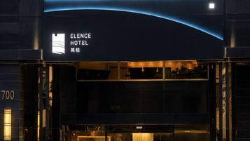 The exterior of the Elence Hotel with a modern design, featuring a prominent entrance and a digital signboard.