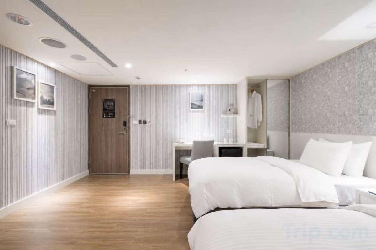 A hotel room with a bed, a desk, and a mirror.