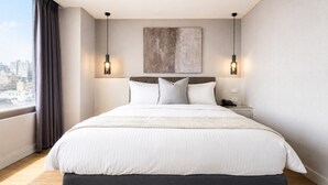 A modern hotel room with a large bed, two wall-mounted lamps, a city view, and a large abstract painting above the bed. - ElEnce Hotel (Taichung)