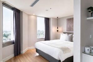 Quarto de hotel moderno com uma cama grande, vista para a cidade e design minimalista.