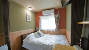 A small, cozy room with a single bed, a wooden desk, an air conditioning unit, and a window with curtains. - C HOTEL -Biei Shirogane Pet Allowed (Biei)