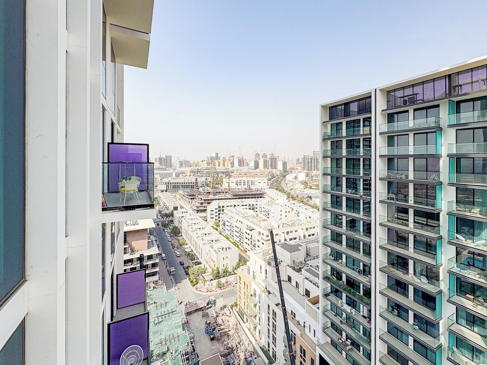 A high-rise building with multiple balconies and a view of a cityscape.