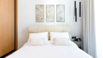 A neatly made bed with white bedding, a headboard, and two wall-mounted artworks.