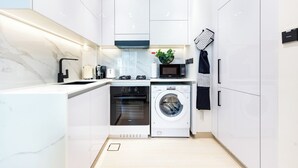 A compact kitchen with a built-in oven, microwave, and washing machine. - Bloomfields Cozy 1Br Binghatti House  (Dubai)