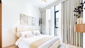 Une chambre moderne avec un grand lit, une vue sur la ville grâce à de grandes fenêtres du sol au plafond et un décor minimaliste.