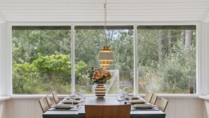 A dining area with a large window, a wooden table, and chairs.