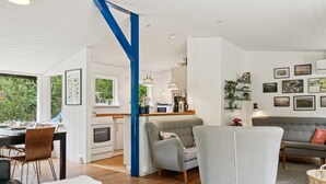 A modern living room with a dining area, a kitchen, and a view of the outdoors.
