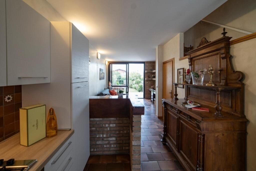 Una cocina con isla de piedra, armarios blancos y un mueble de madera decorado.
