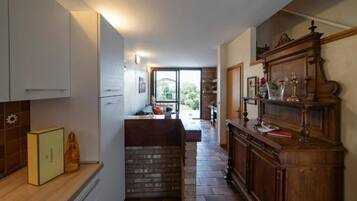 Una cocina con isla de piedra, armarios blancos y un mueble de madera decorado.