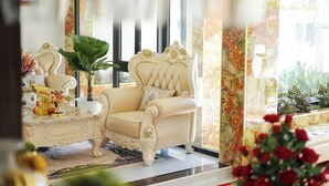 A luxurious room with a plush cream-colored sofa, a matching armchair, and a decorative table with a vase and plant. - Sea View Hotel Phan Thiet (Tien Thanh)