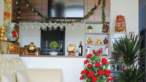 A living room with a sofa, a TV, a shelf with decorative items, and a potted plant. - Sea View Hotel Phan Thiet (Tien Thanh)