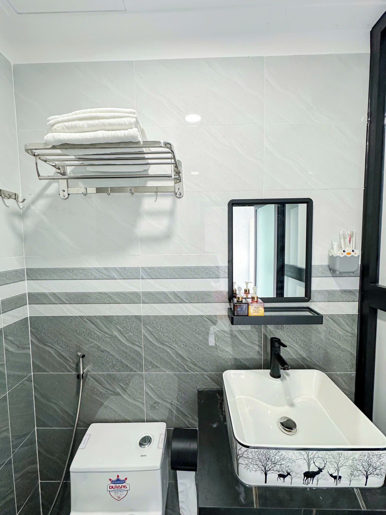 A bathroom with a white sink, a mirror, a towel rack, and a toilet.