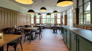 A spacious restaurant with wooden paneling, large windows, and pendant lighting. - Wohnpark Hotel (Heppenheim)
