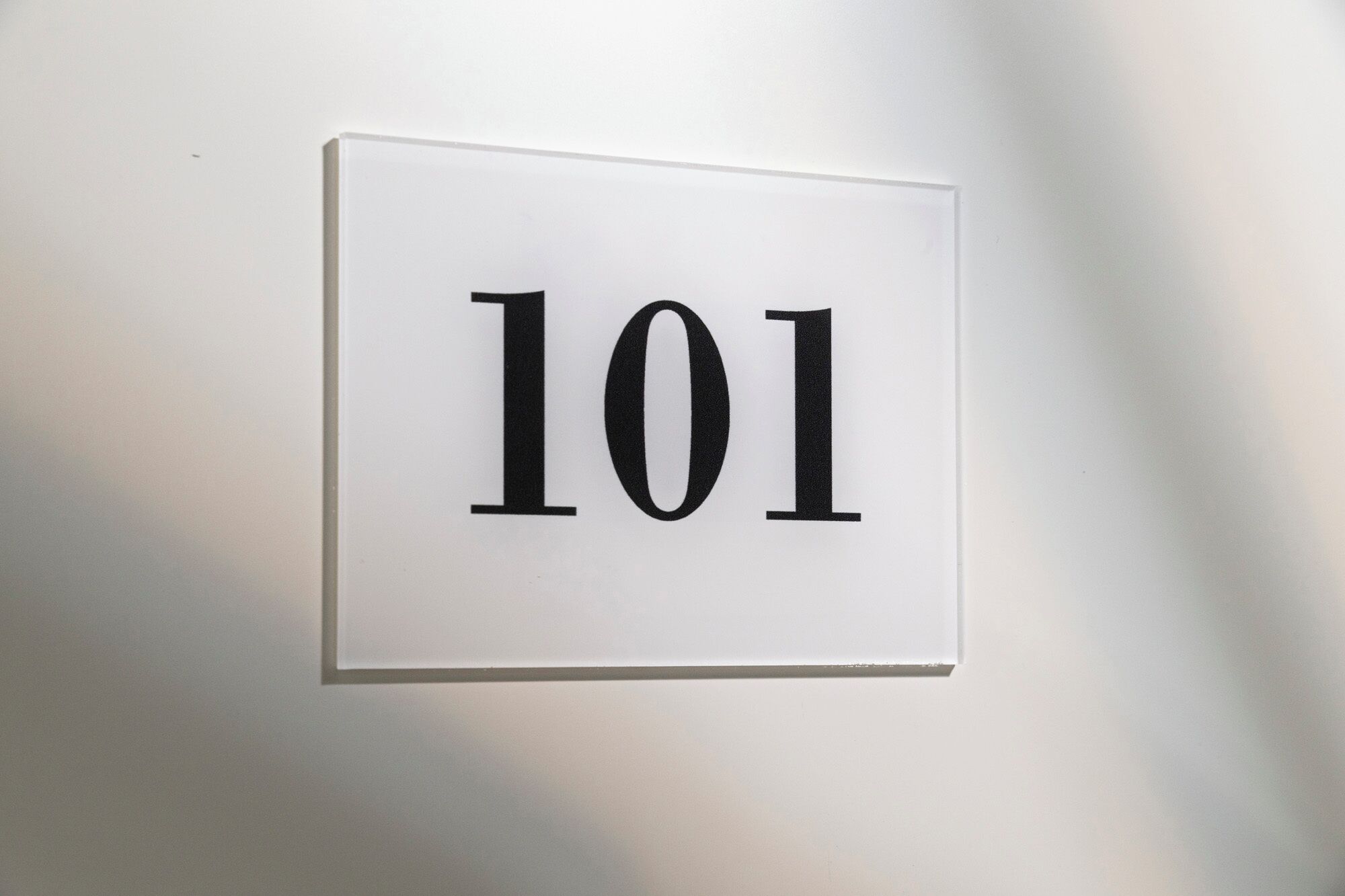 Ein weißes Schild mit der Nummer 101 an einer Wand.