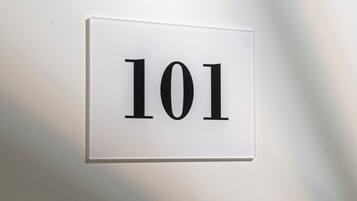Ein weißes Schild mit der Nummer 101 an einer Wand.