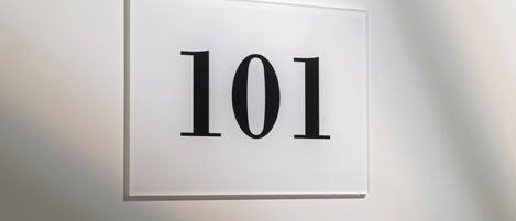 Un letrero blanco con el número '101' en una pared.