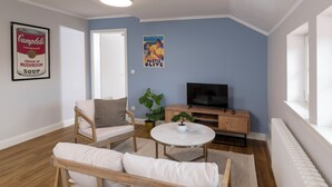 A living room with a sofa, a TV, a small table, and a potted plant. - Wohnpark Hotel (Heppenheim)