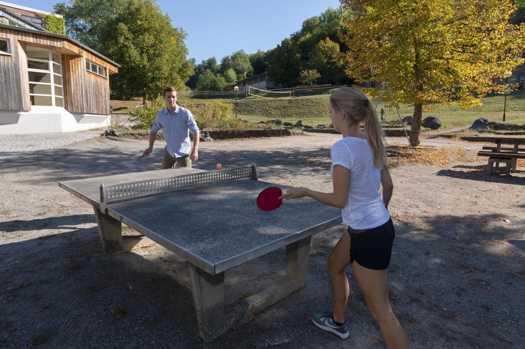 A ping pong table in an outdoor area with a building in the background.