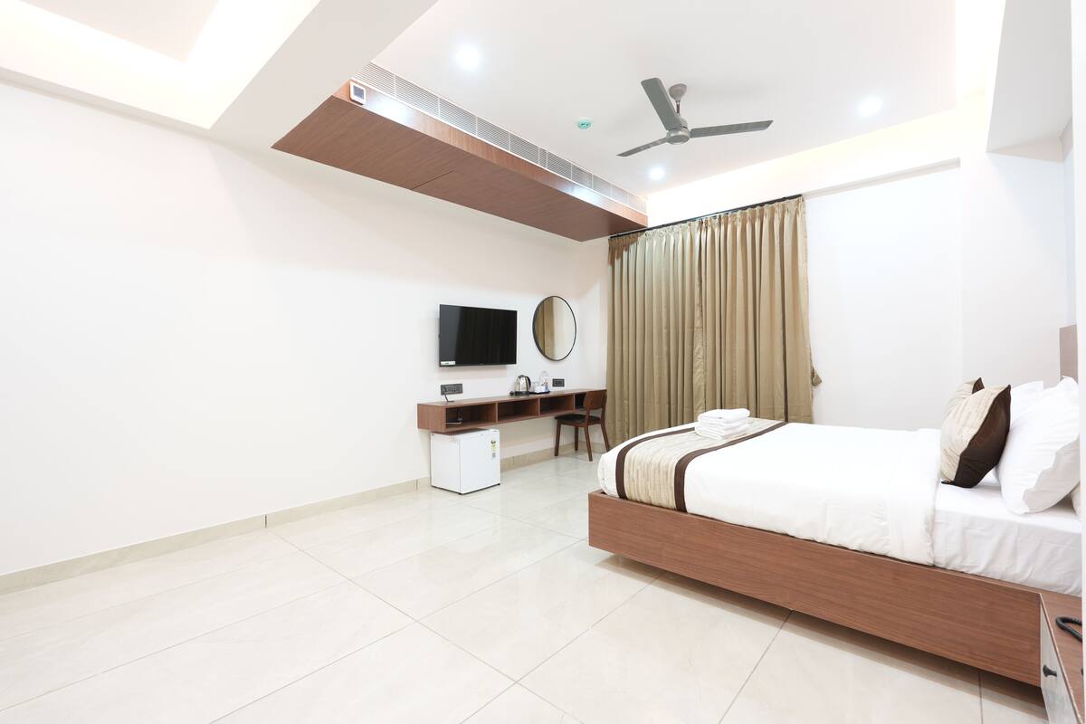 A modern bedroom with a bed, desk, chair, and a ceiling fan.