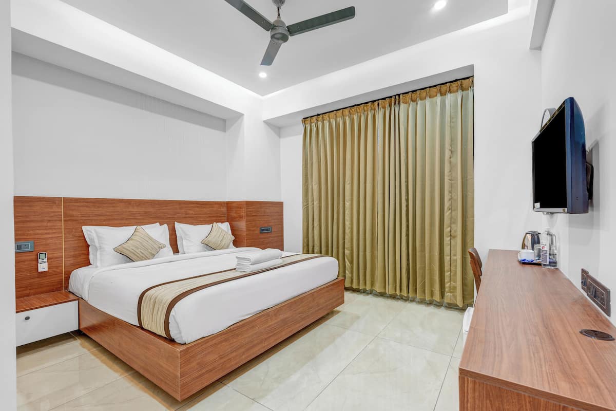 A modern hotel room with a wooden bed, a desk, a flat-screen TV, and a ceiling fan.