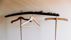 A wooden rack with three hangers, two of which are empty. - Vitalenta Agriboutique (Pienza)