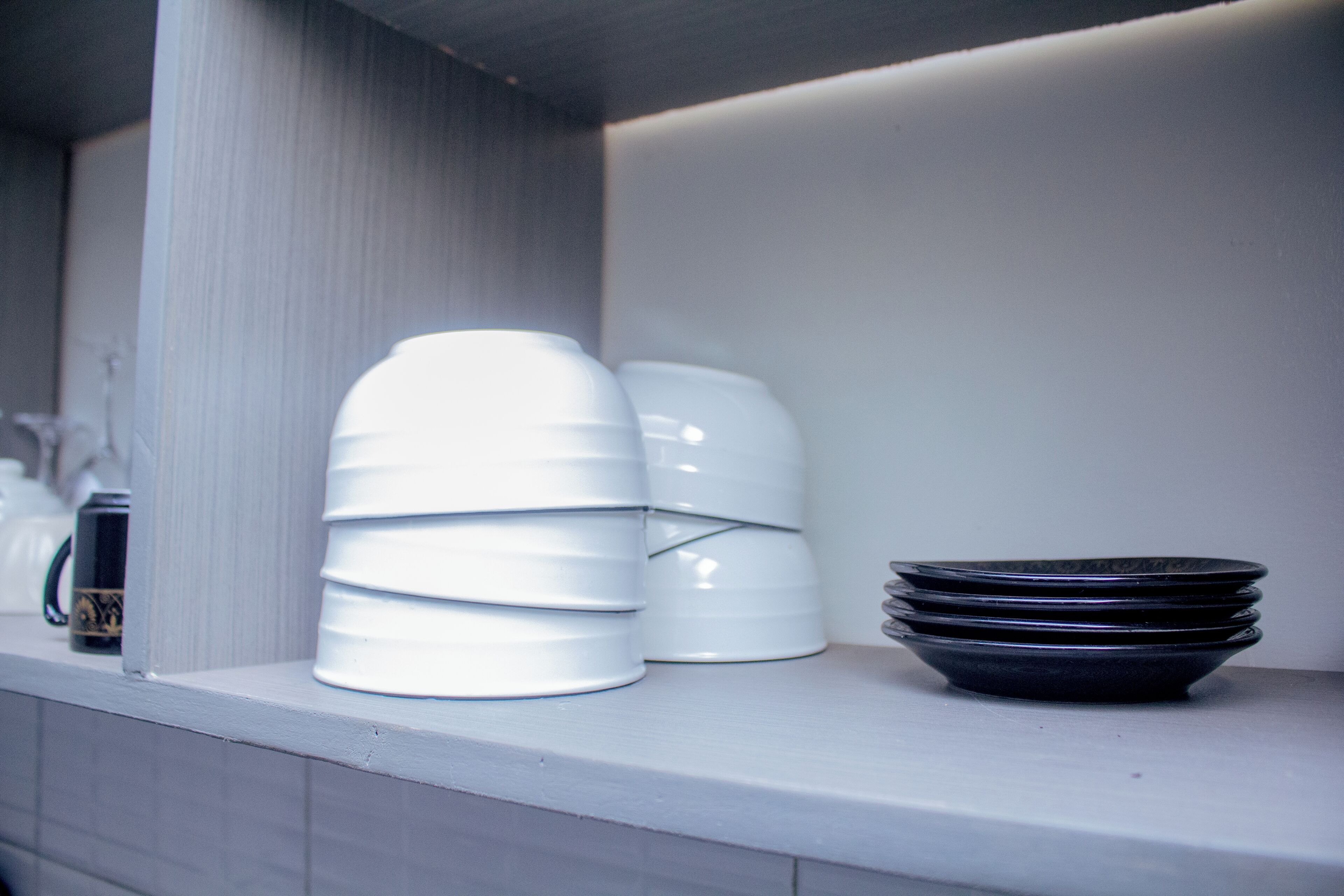 A kitchen counter with stacked white and black dishes.