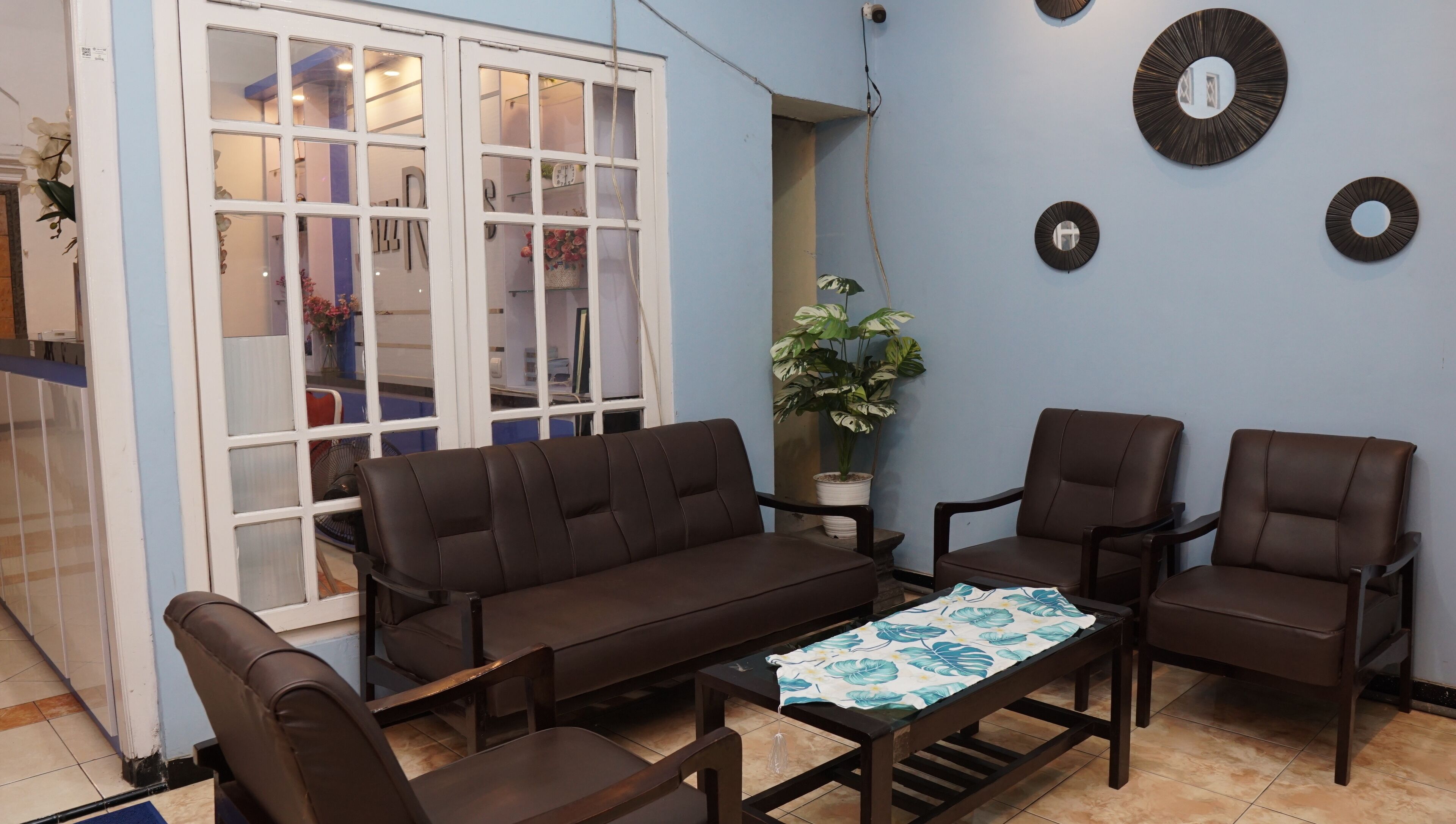 A living room with a sofa, two armchairs, a coffee table, and a potted plant.