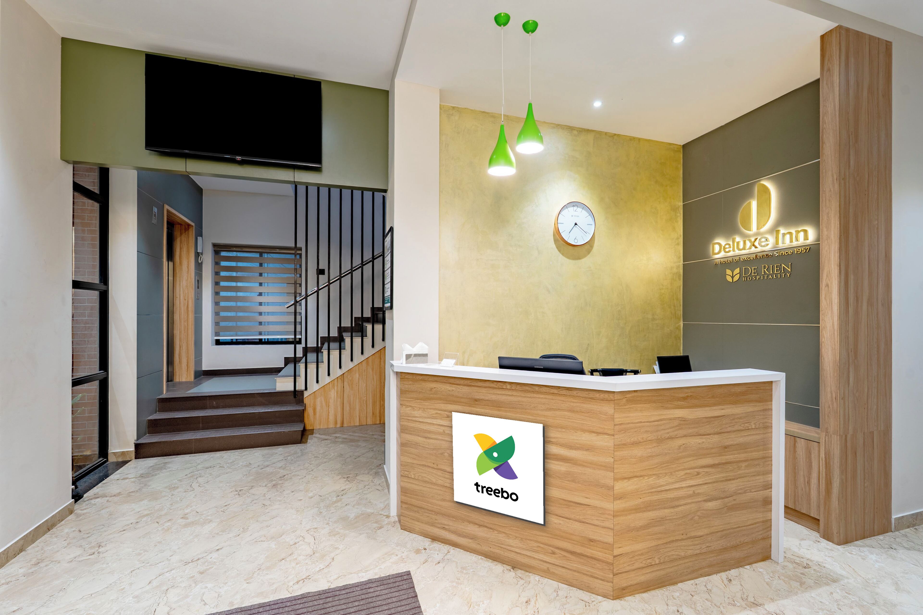 A hotel reception desk with a clock, a digital screen, and a logo.