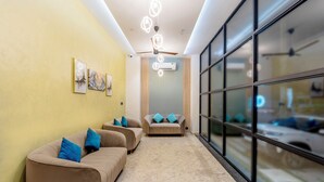 Un hall d’hôtel moderne avec des canapés de couleur beige, un ventilateur de plafond et une grande fenêtre donnant sur l’extérieur.