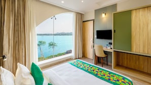 Une chambre d’hôtel équipée d’un lit, d’un bureau, d’une chaise, d’une télévision et offrant une vue sur une étendue d’eau.