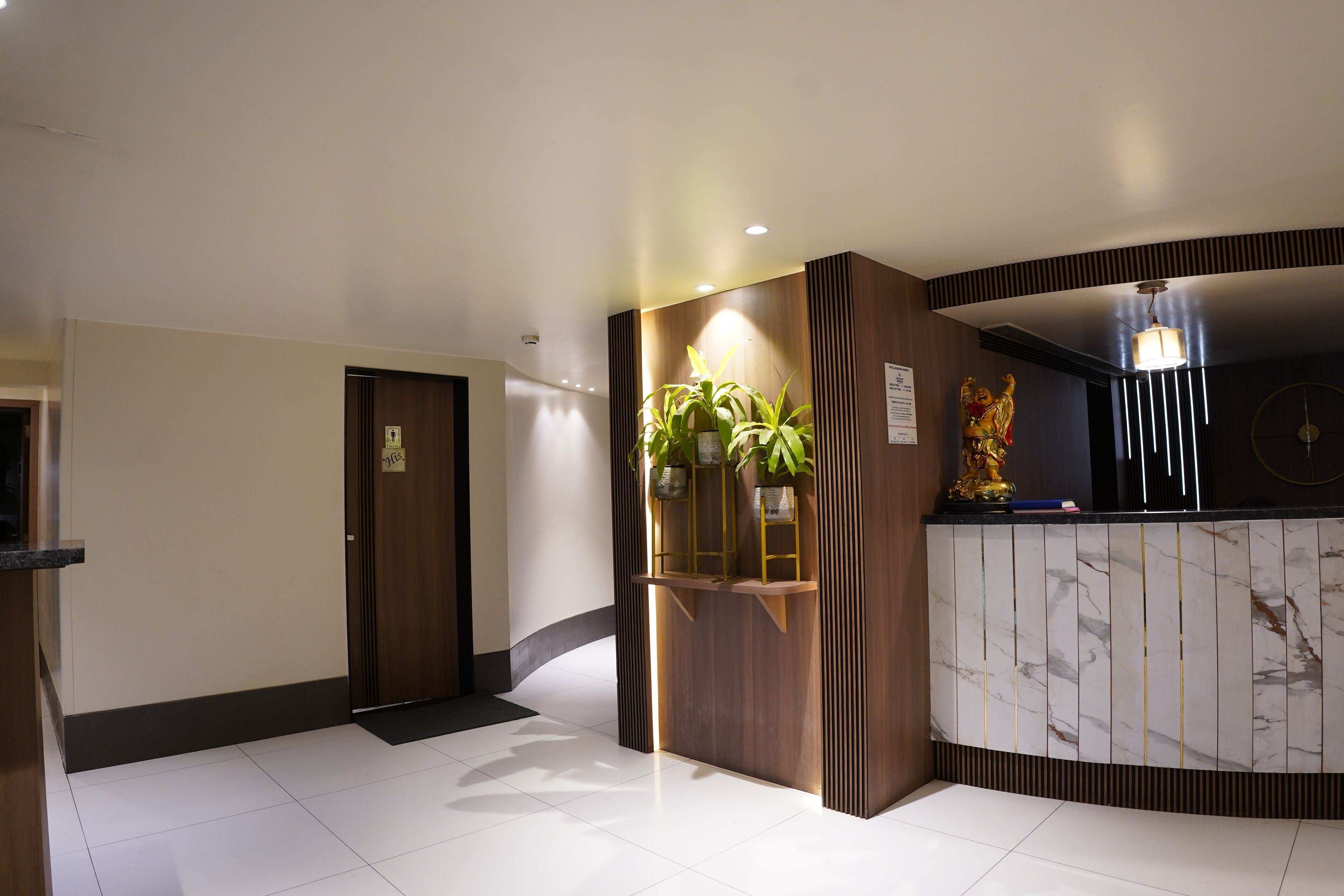 A reception area with a marble counter, wooden paneling, and a potted plant.