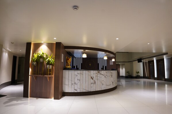 A modern reception area with a marble counter, wooden accents, and potted plants.