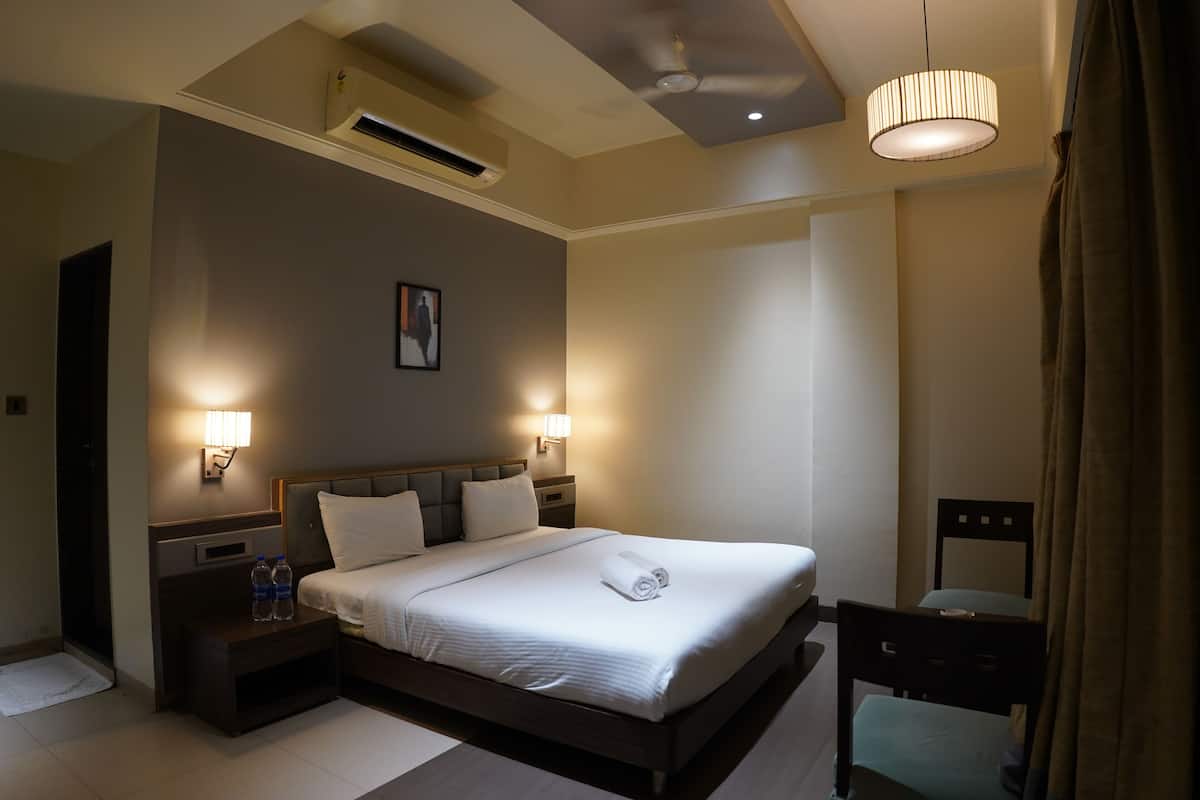 Habitación de hotel con una cama grande, mesitas de noche, una silla y un ventilador de techo.
