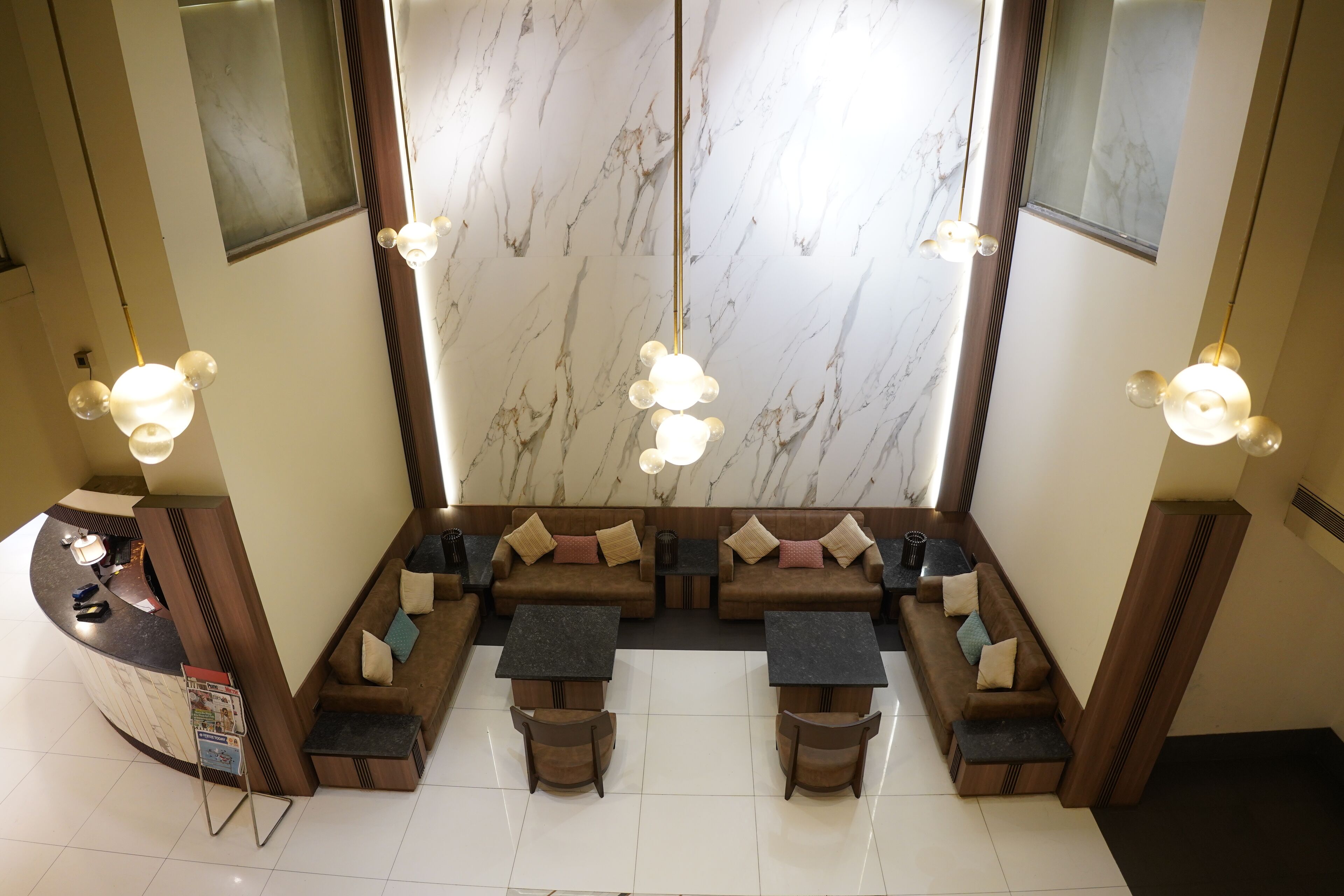A modern lobby with a marble wall, seating area, and a reception desk.