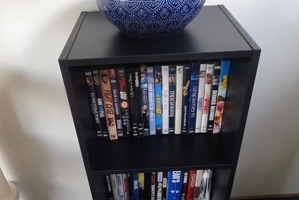 Une bibliothèque contenant une variété de DVD et de livres.