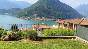Paisagem montanhosa com um lago, uma pequena cidade e edifícios residenciais com telhados de telha vermelha.