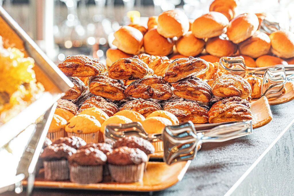 A buffet with various baked goods including muffins and pastries.