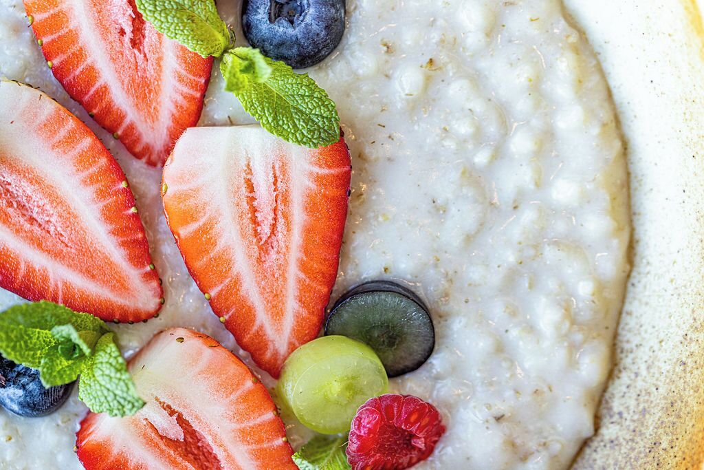 A bowl of oatmeal with strawberries, blueberries, grapes, and raspberries.