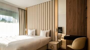 A modern bedroom with a large bed, bedside tables, a desk, and a chair.