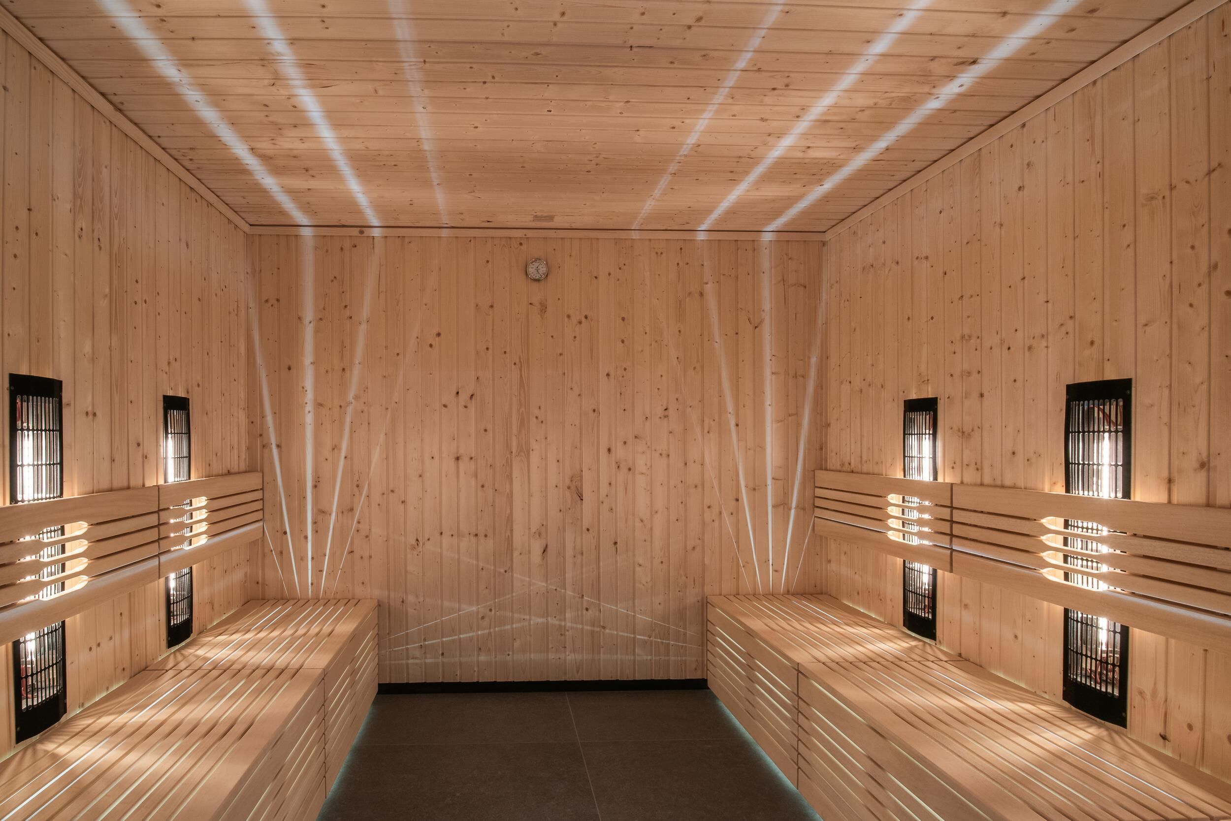 Una sauna con pareti e panche in legno, caratterizzata da panche a listare e piccole finestre.