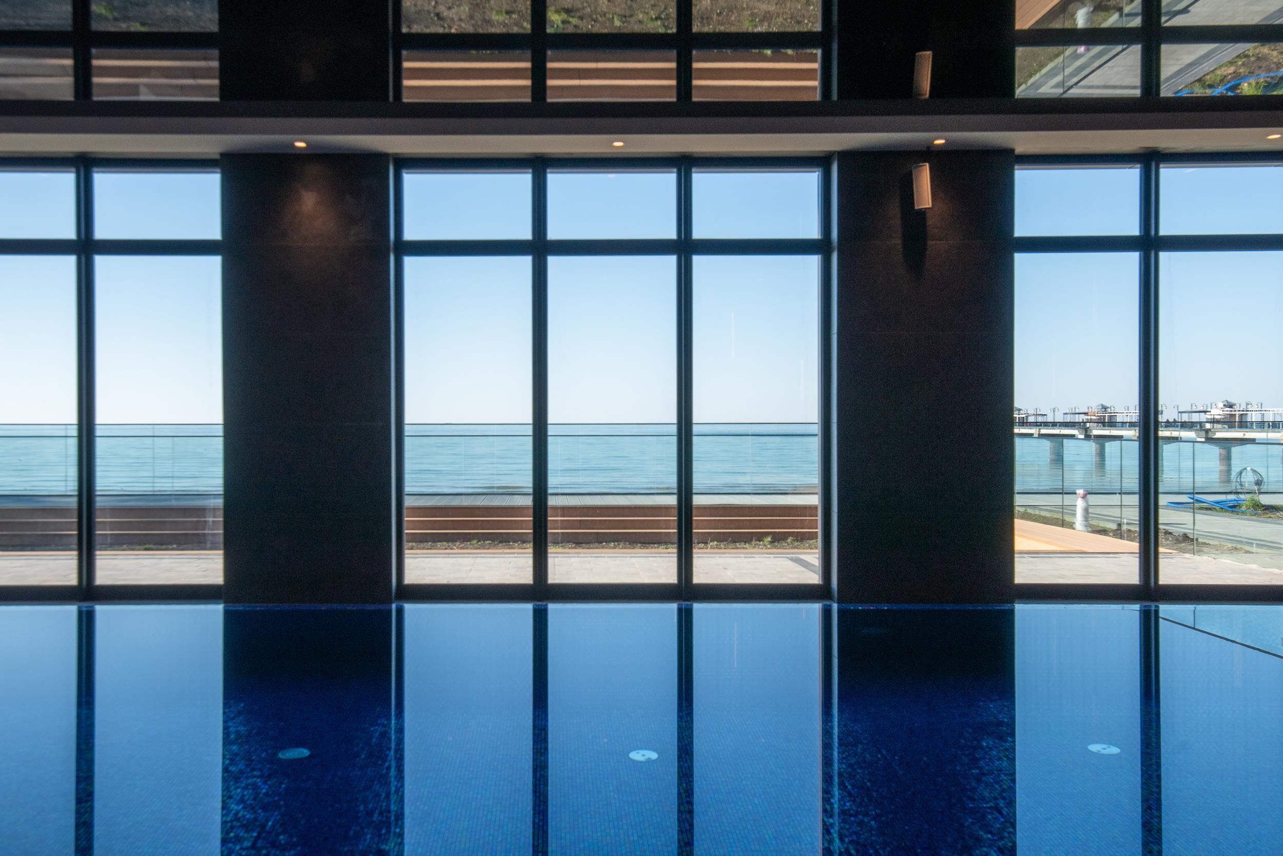 Une piscine offrant une vue dégagée sur la mer grâce à de grandes baies vitrées.