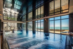 A large indoor swimming pool with a view of the beach through large windows. - Baltic View Resort & Spa, A Member Of Radisson Individuals (Miedzyzdroje)